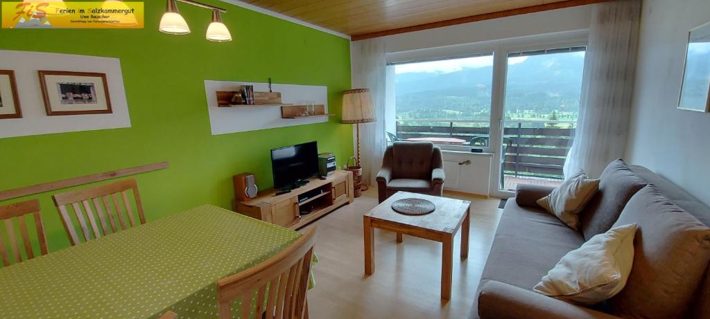 een woonkamer met groene muren en een bank en een tafel bij Apartment Urlaubstraum by FiS - Fun in Styria in Bad Mitterndorf