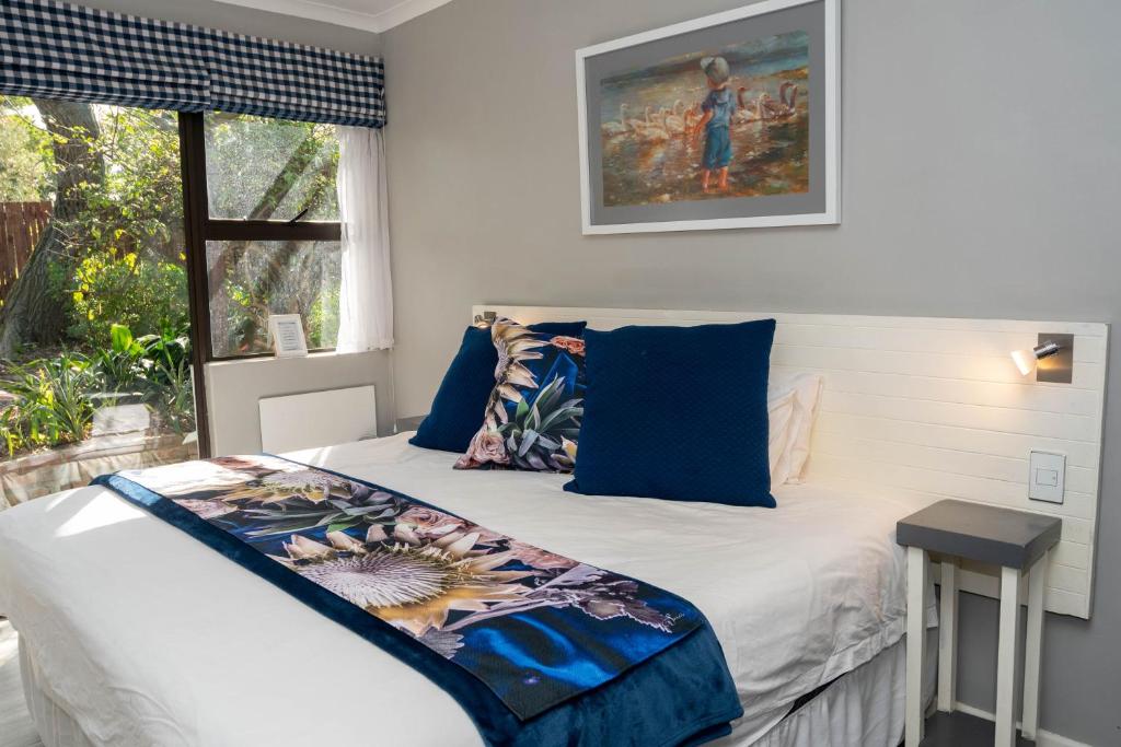 a bedroom with a bed with blue pillows and a window at Rouana Guest Farm in Stellenbosch
