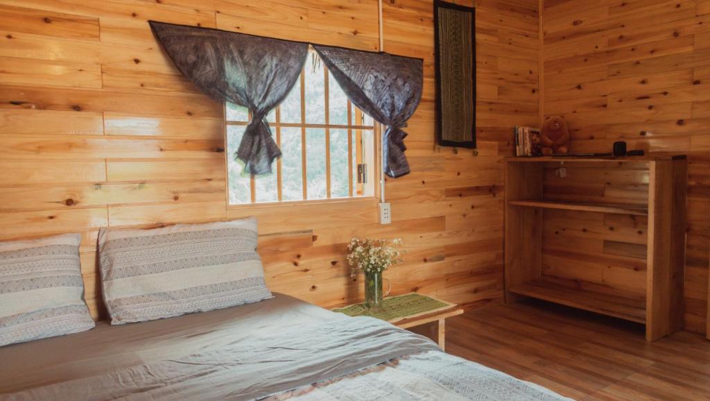 a bedroom with a bed and a window in a log cabin at Joy House Sapa in Sapa