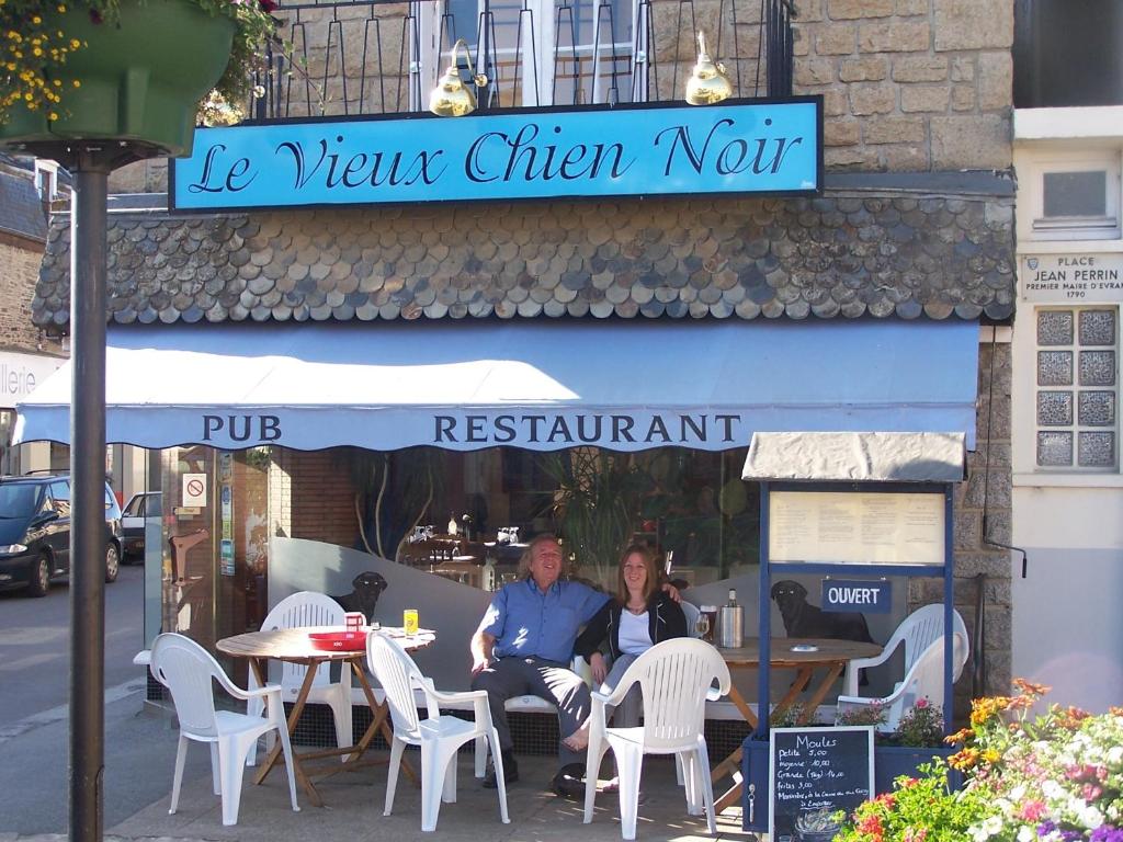a man and woman sitting at a table outside a restaurant at Le Vieux Chien Noir in Évran