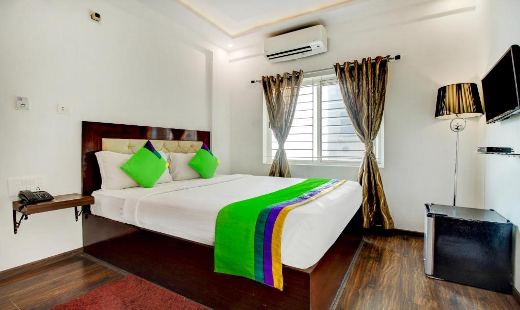 a bedroom with a large bed and a television at Treebo Trend The Sai Leela Suites R T Nagar in Bangalore