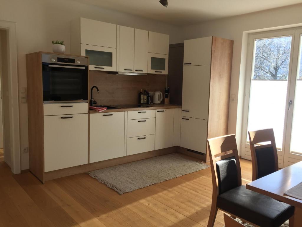 cocina con armarios blancos, mesa y ventana en Ferienwohnung Neureiter en Golling an der Salzach