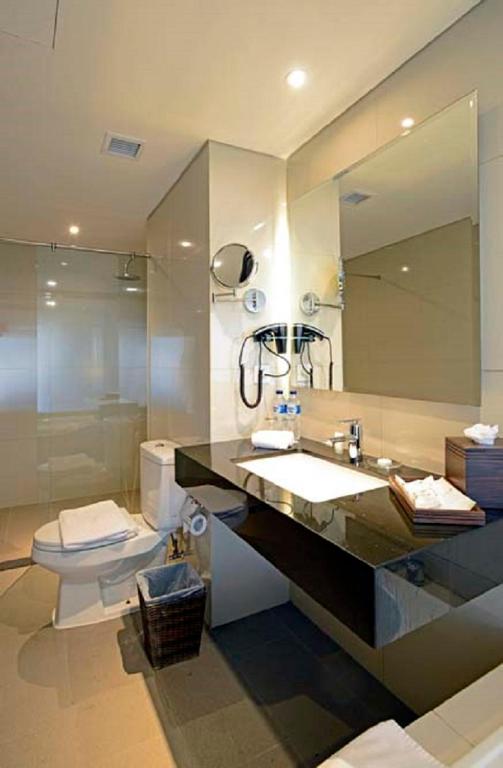 a bathroom with a sink and a toilet and a mirror at Discovery Ancol in Jakarta
