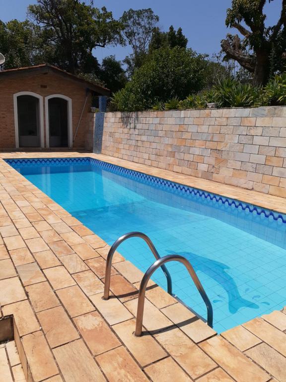 a swimming pool with a brick wall next to at Sítio Pandoro in Atibaia