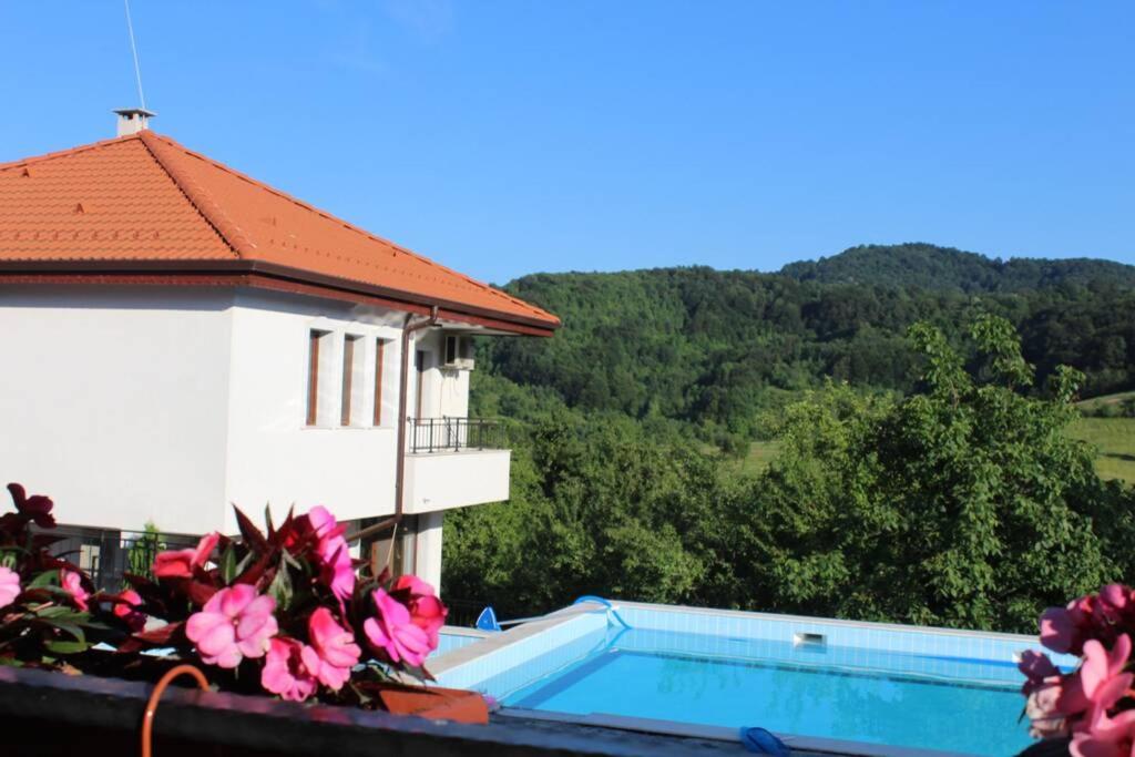 - une vue sur un bâtiment avec une piscine et des fleurs dans l'établissement Бадевски рай- къща София, à Veliko Tarnovo