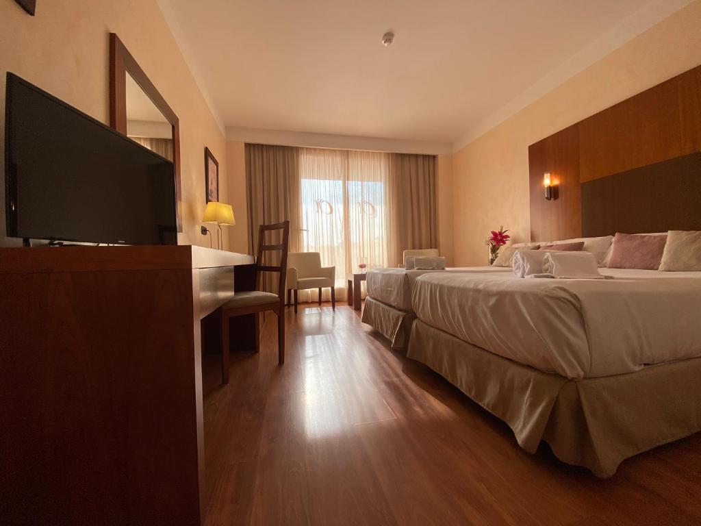 a hotel room with two beds and a flat screen tv at Hotel Montera Plaza in Los Barrios