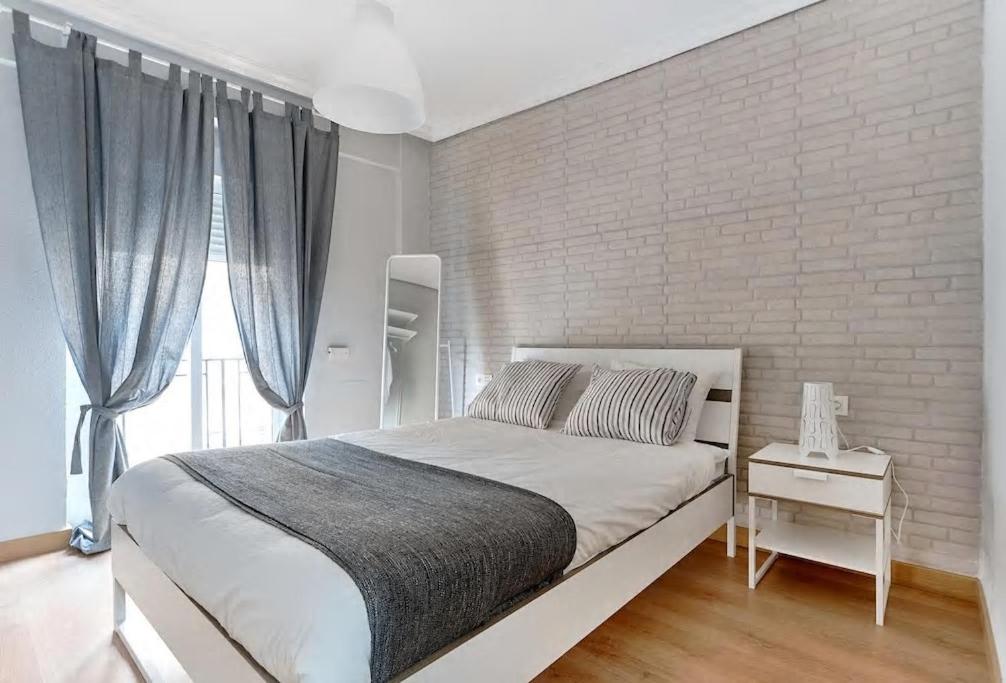 1 dormitorio con 1 cama grande y pared de ladrillo en Apartamento Morales - 2 habitaciones, espacioso y tranquilo junto a Hospital, en Murcia