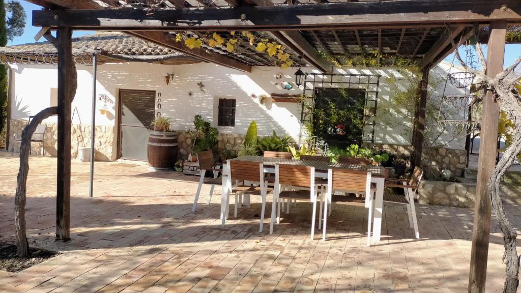 un patio con mesa y sillas bajo una pérgola en Casa Rural El Olivar de las Pepinas, en Yecla