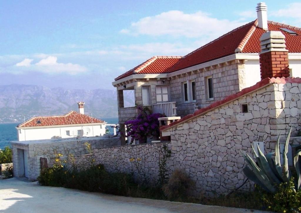 a house with a stone wall at Apartments Villa Vanja in Povlja