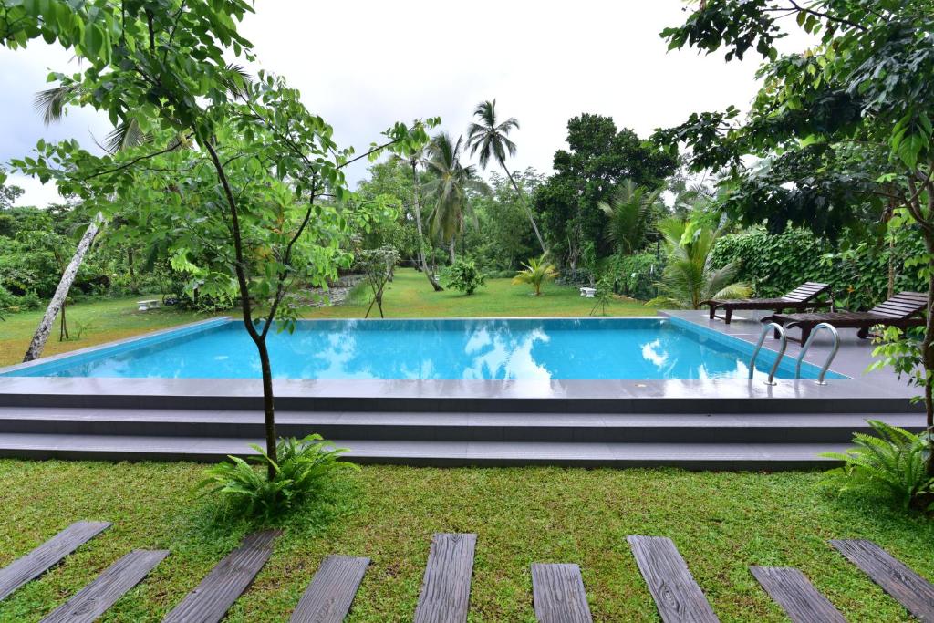 a swimming pool in the middle of a garden at Iain Lake Winds Villa in Galle