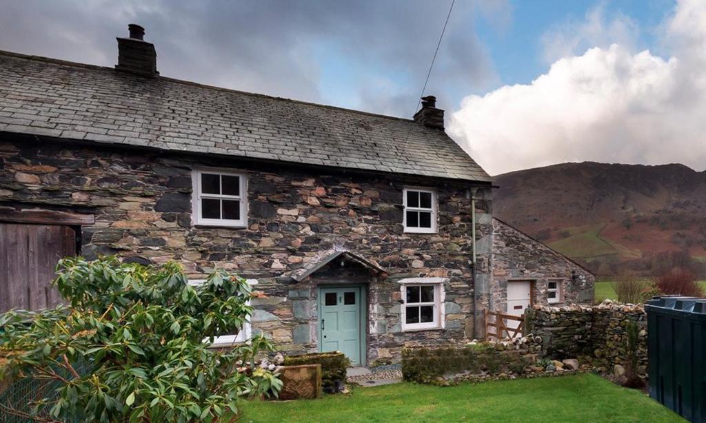 an old stone house with a blue door at Yew Tree Cottage Borrowdale in Rosthwaite