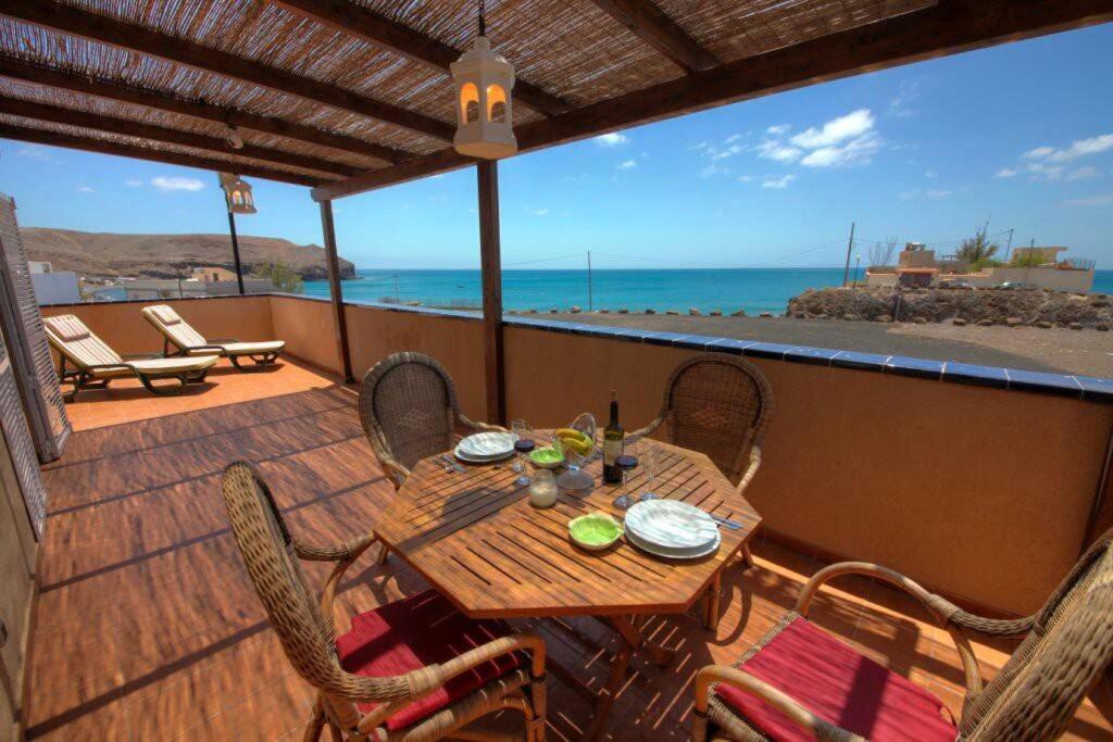 a wooden table and chairs on a balcony with the ocean at Wohnung direkt am Meer in La Lajita in Lajita