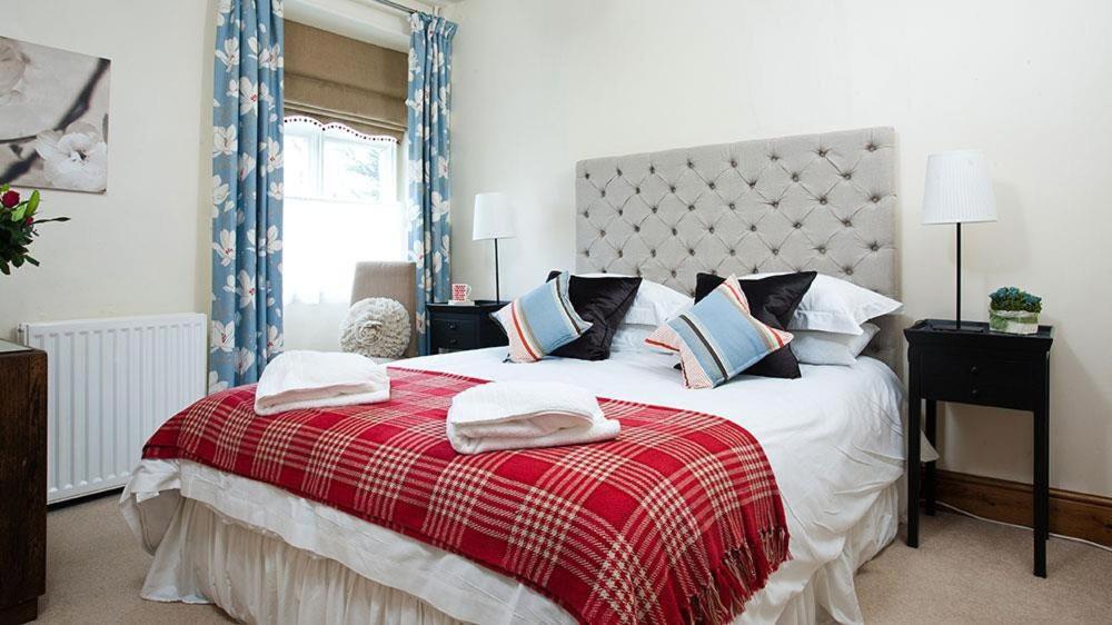 a bedroom with a large bed with a red blanket at Riverbank At Stepping Stones in Ambleside