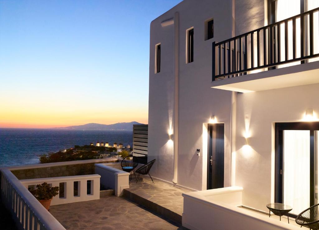 a balcony with a view of the ocean at sunset at Epic Mykonos in Mikonos