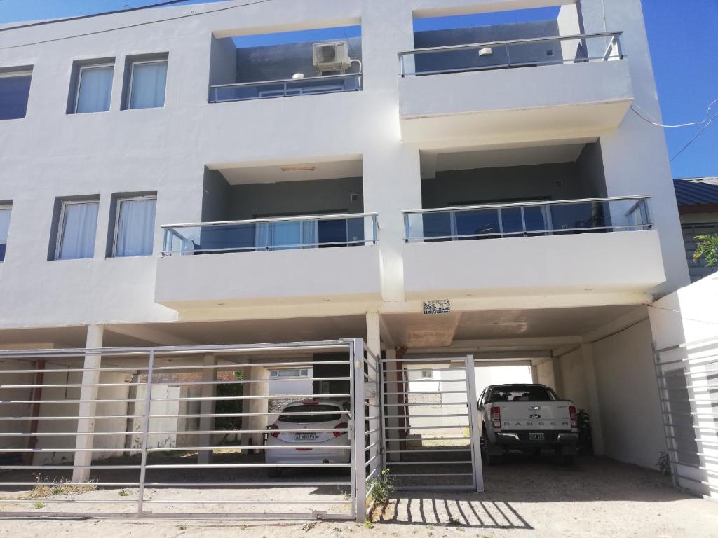 a white building with a parking garage with cars in it at Departamentos LG in Las Grutas
