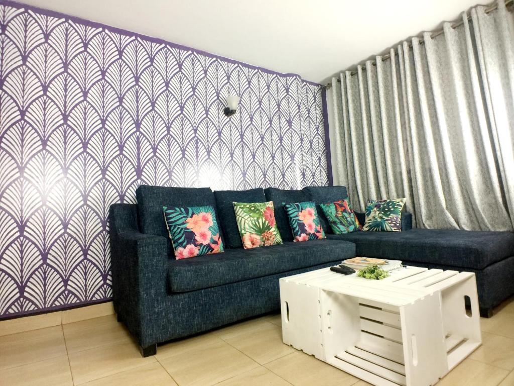 ein Wohnzimmer mit einem Sofa und einem Tisch in der Unterkunft Studio Ghibli 1BR1B in Kampala