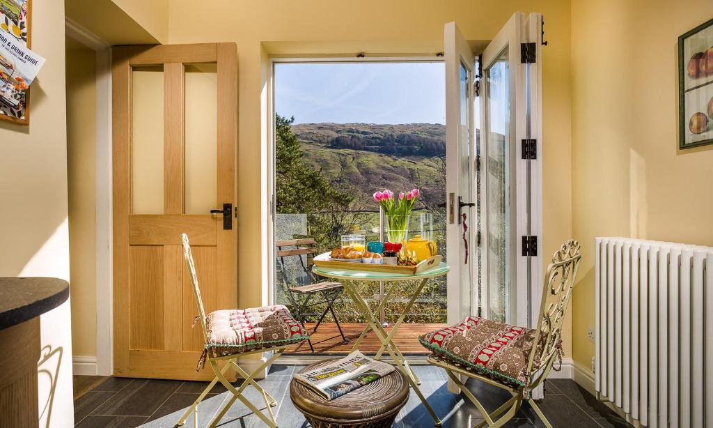 a room with a table and chairs and a balcony at South Stonethwaite Cottage in Windermere