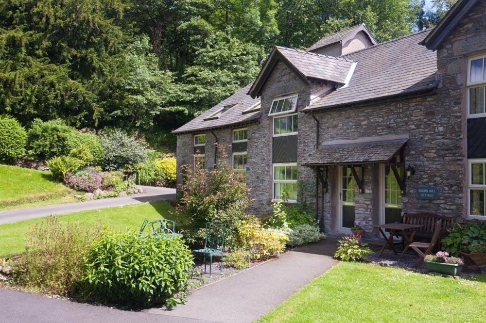 una antigua casa de piedra con una mesa de picnic en el patio en Gilpin View en Crosthwaite