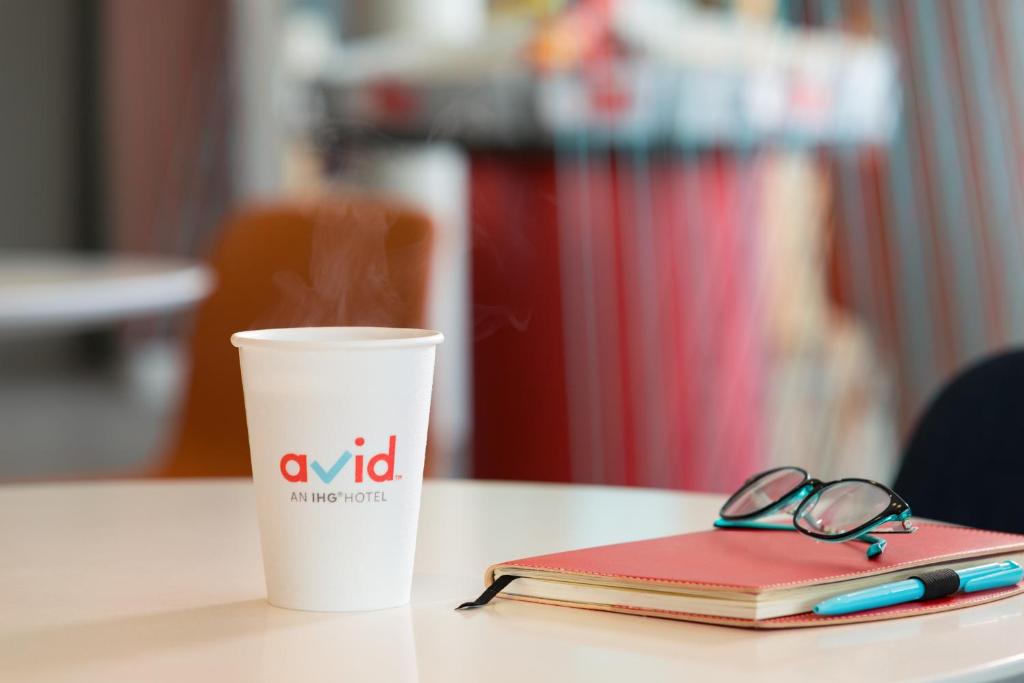 a cup of coffee and a notebook with a pen and glasses at avid hotels - Sioux City - Downtown, an IHG Hotel in Sioux City