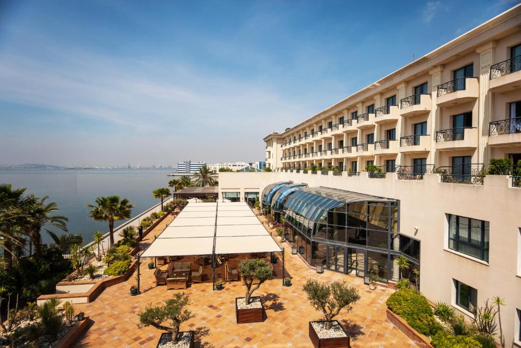 ein großes Gebäude mit einem Innenhof mit Tischen und Bäumen in der Unterkunft Barceló Concorde Les Berges du Lac in Tunis