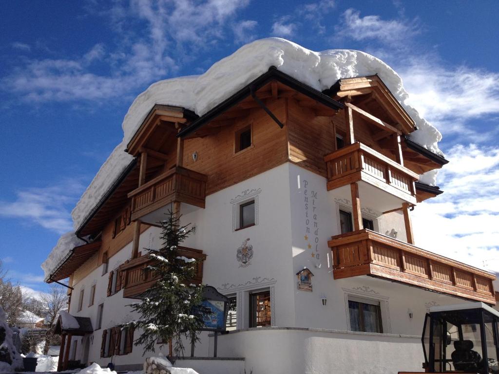 a large building with a snow covered roof at Pension Mirandola in Colfosco