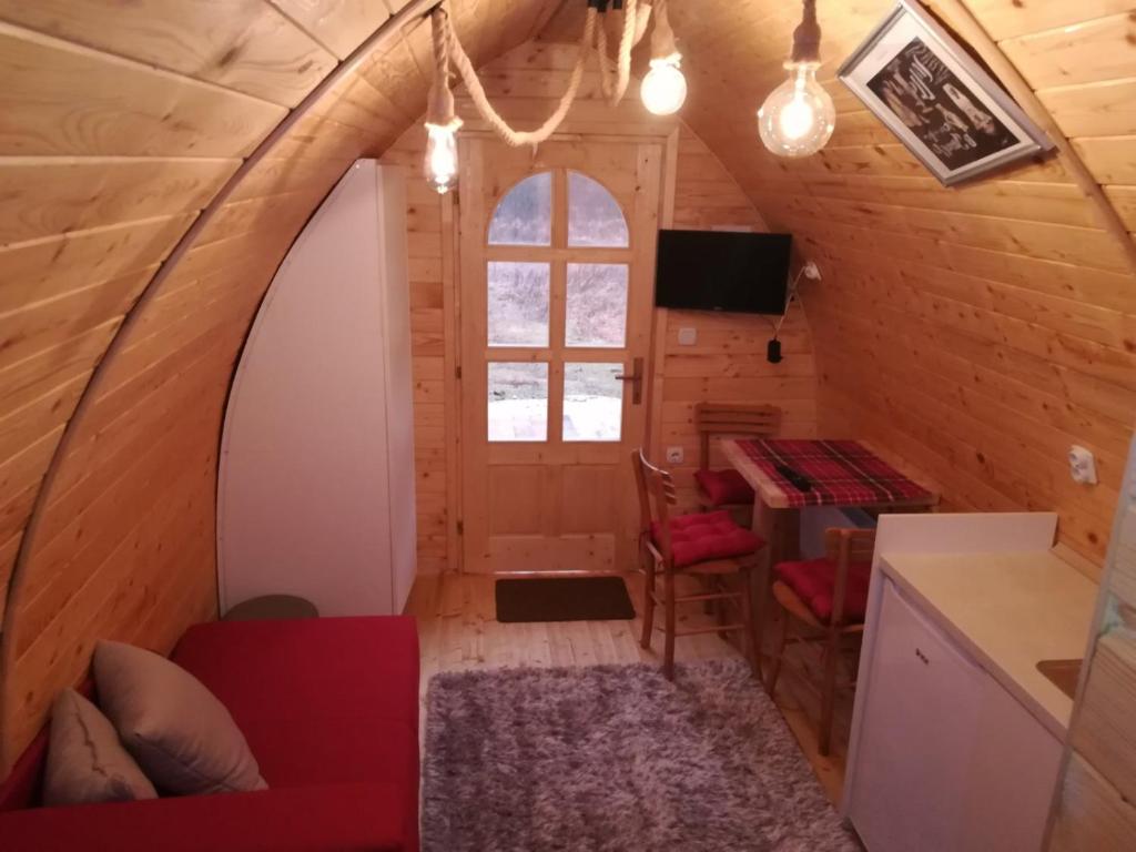 una stanza in una casetta minuscola con un divano rosso di Vila Jelena - BUNGALOV a Crni Vrh