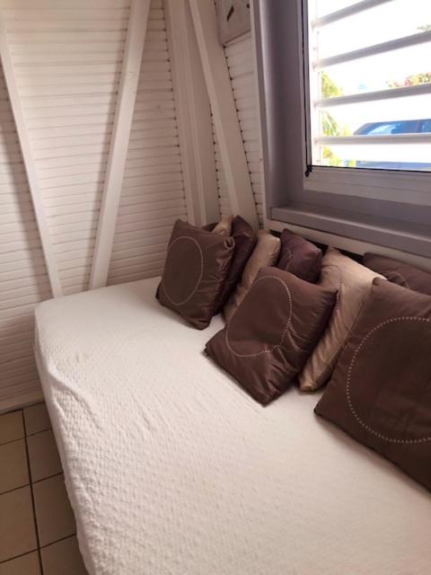 a couch with pillows sitting next to a window at TI-MANGO VUE MER in Sainte-Anne