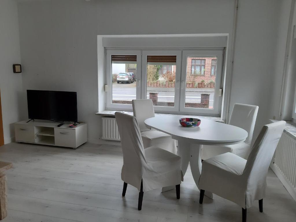 a white dining room with a white table and chairs at Ferienhaus am alten Postamt in Hanerau-Hademarschen