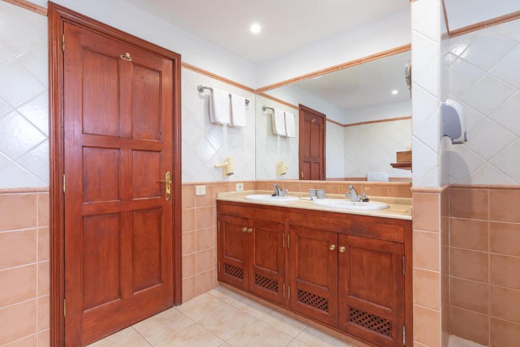 a bathroom with a sink and a wooden door at Surfescape Fuerteventura in Lajares