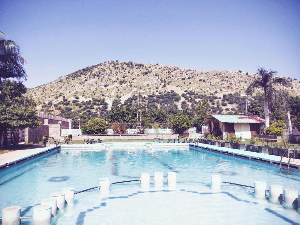 a large swimming pool with a mountain in the background at Ritumbhara Hotel & Resort in Alwar