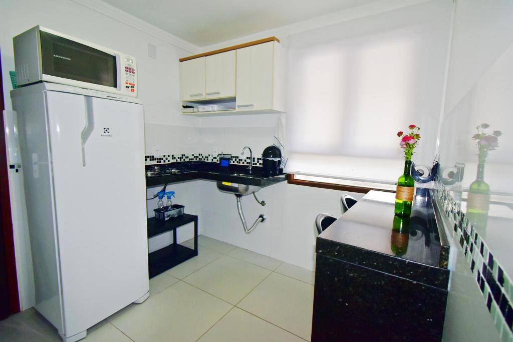 uma pequena cozinha com um frigorífico e um balcão em Studios Bombinhas em Bombinhas