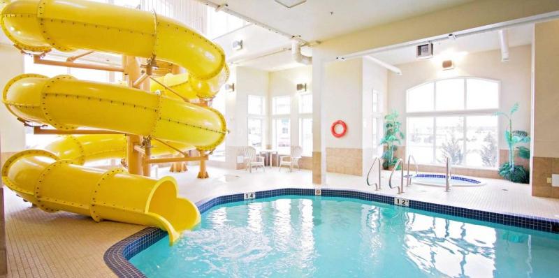 a large swimming pool with a slide in a building at Service Plus Inns & Suites Drayton Valley in Drayton Valley