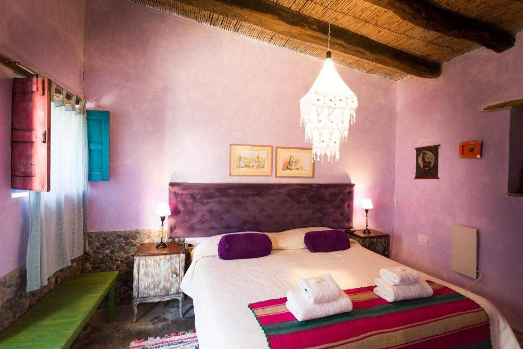 Un dormitorio con una cama con paredes moradas y una lámpara de araña. en Viracocha Art Hostel Cachi en Cachí