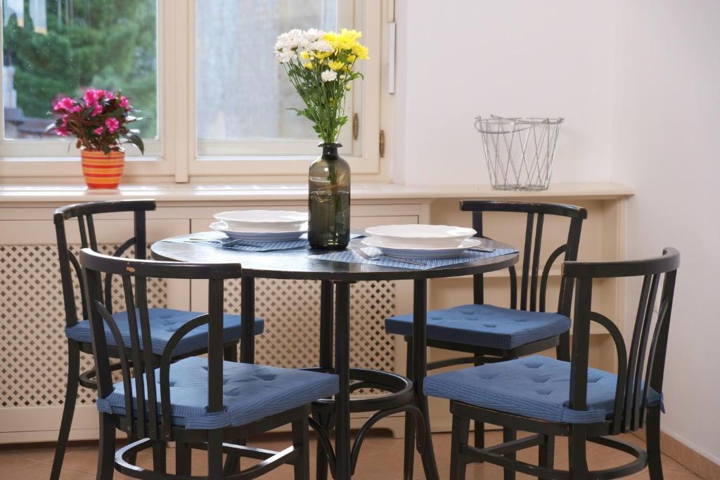 a table with four chairs and a vase with flowers at Pawlansky Apartments No.4 in Prague