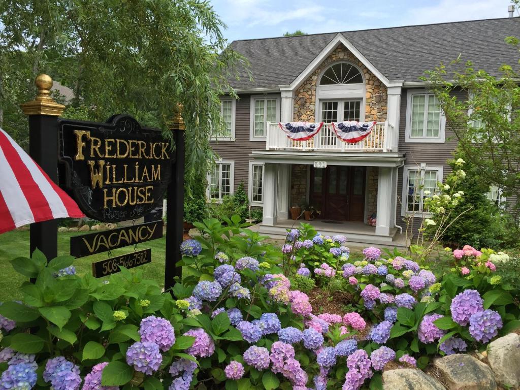 a house with a sign in a garden with flowers at Frederick William House in Falmouth