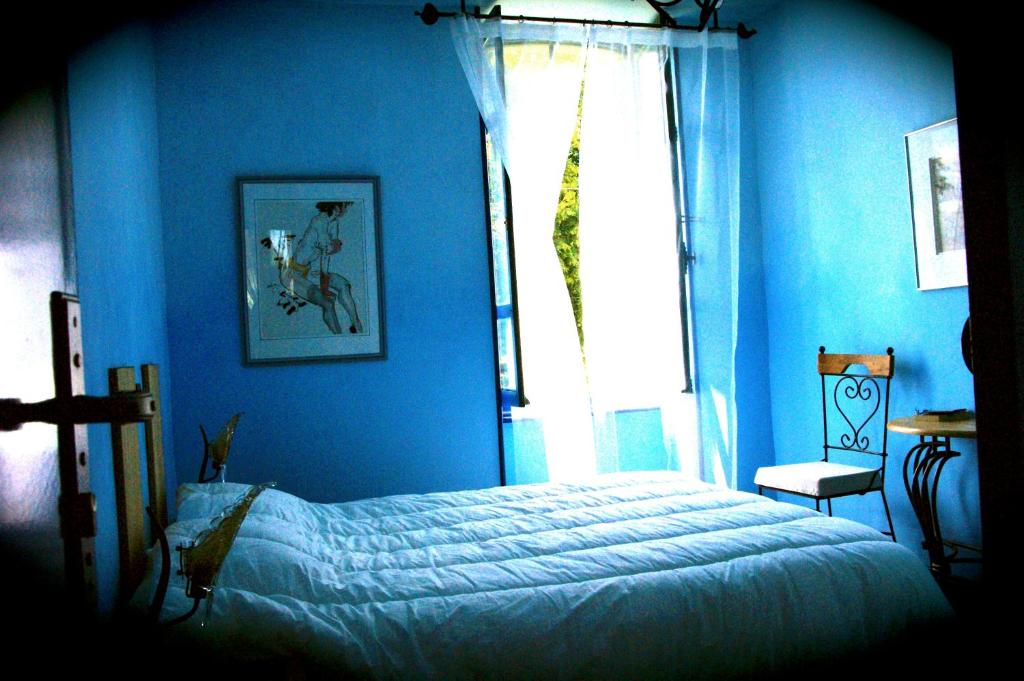 a blue bedroom with a bed and a window at Auberge Magnette in Audes