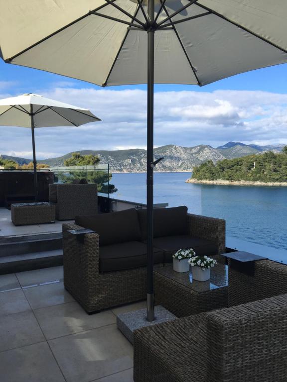 une terrasse avec un canapé et un parasol dans l'établissement High View-A Seaside Villa With Huge Jacuzzi, à Račišće