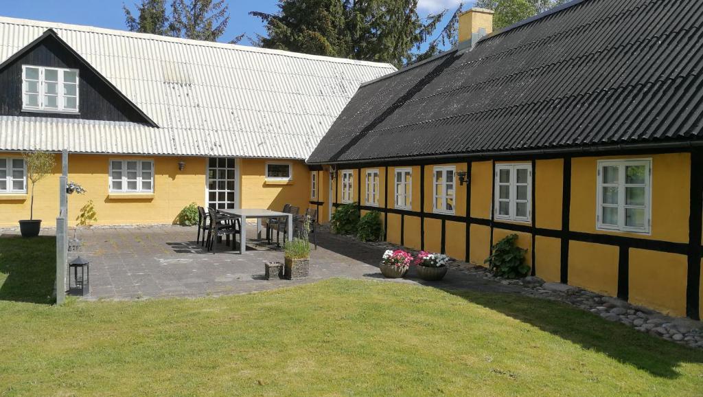 una casa amarilla con una mesa delante en Fædrelandet Ferielejlighed & Turridning en Læsø