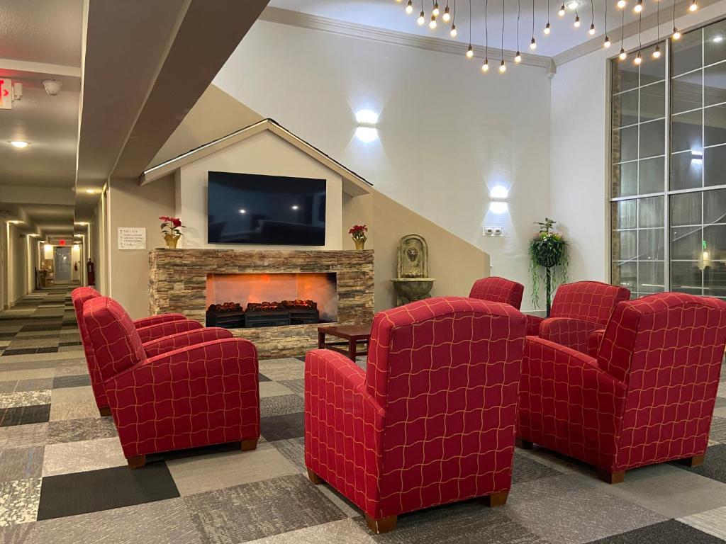 a living room with red chairs and a fireplace at University Inn of Carbondale in Carbondale