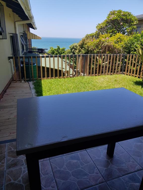 a black bench sitting on a patio with the ocean at Ocean rush turtle in Zinkwazi Beach