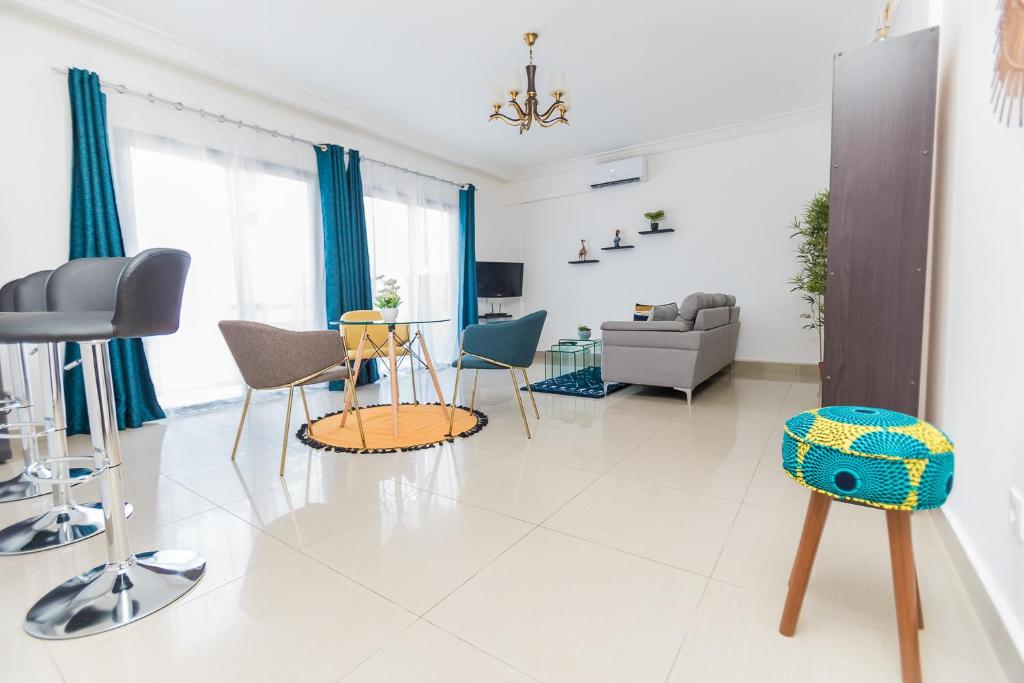 a white living room with chairs and a table at Appartement cosy à la plage - Pointe Noire in Pointe-Noire