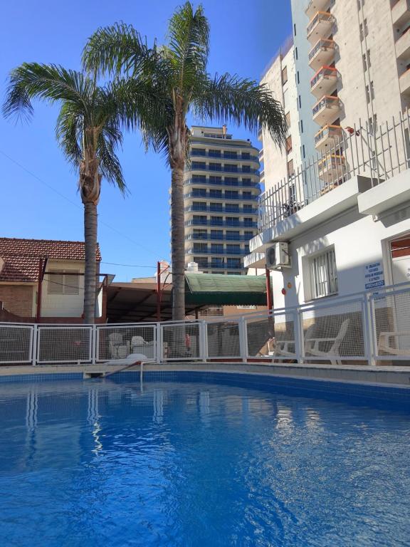 uma grande piscina com palmeiras e edifícios em Hotel Brisas em Villa Carlos Paz