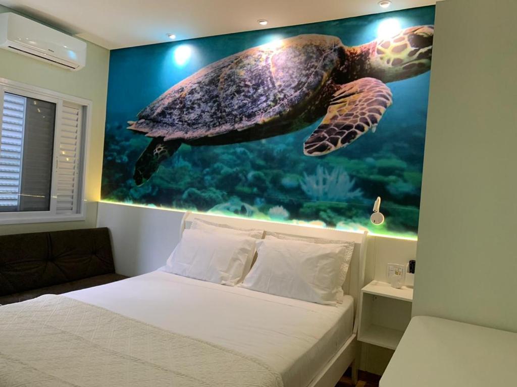 um quarto com uma pintura de tartaruga na parede em Suite Turtle no Guarujá
