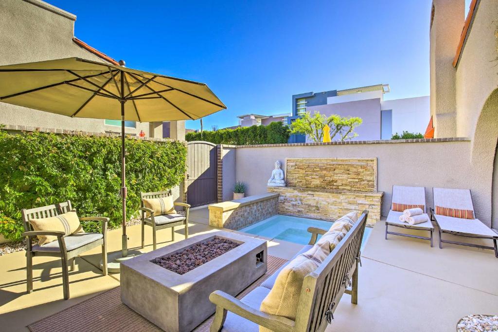 Un patio con una mesa y sillas y una sombrilla. en Dtwn Palm Springs Condo BBQ, Pool, Fire Pit, etc!, en Palm Springs