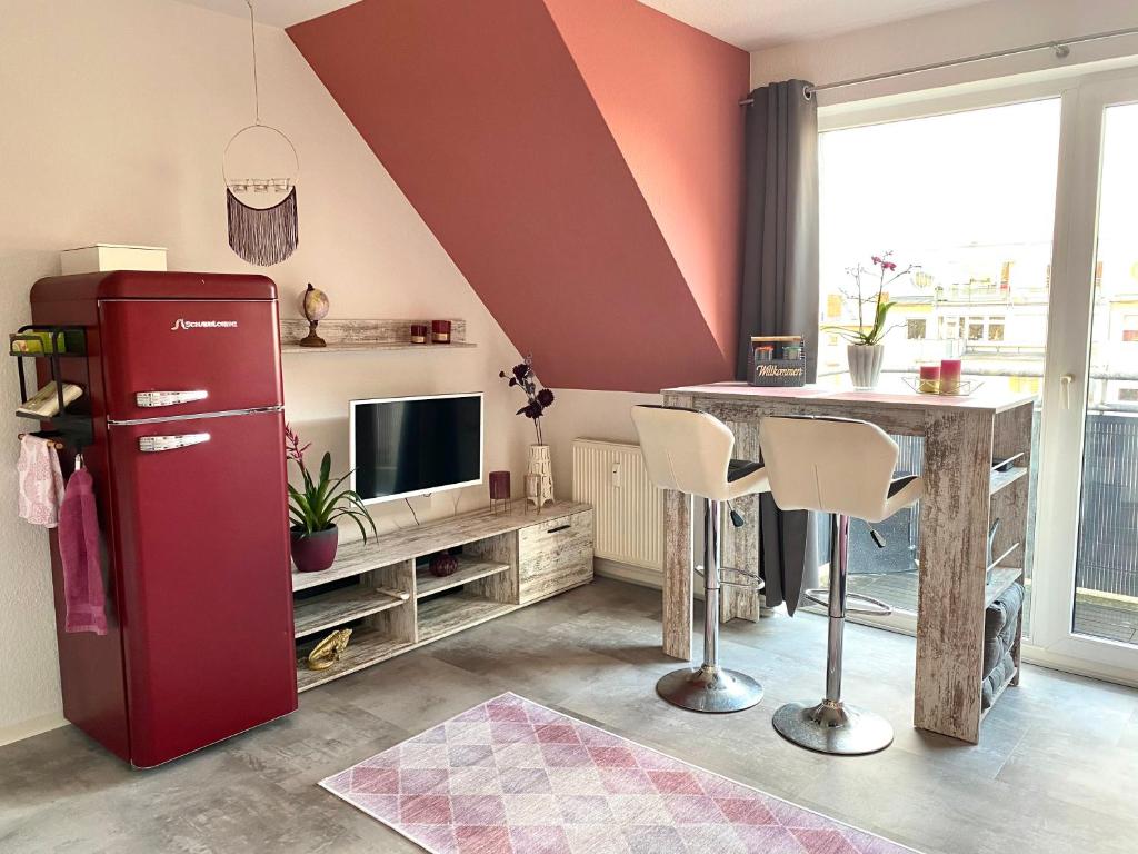 Cette chambre comprend un réfrigérateur rouge et une table. dans l'établissement Eigenes Apartment im Herzen der Stadt mit Balkon und WLAN II, à Cottbus