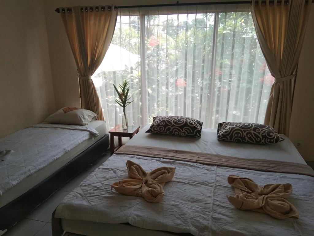 2 letti in una camera con una grande finestra di SunwuKong Guest House ad Ubud