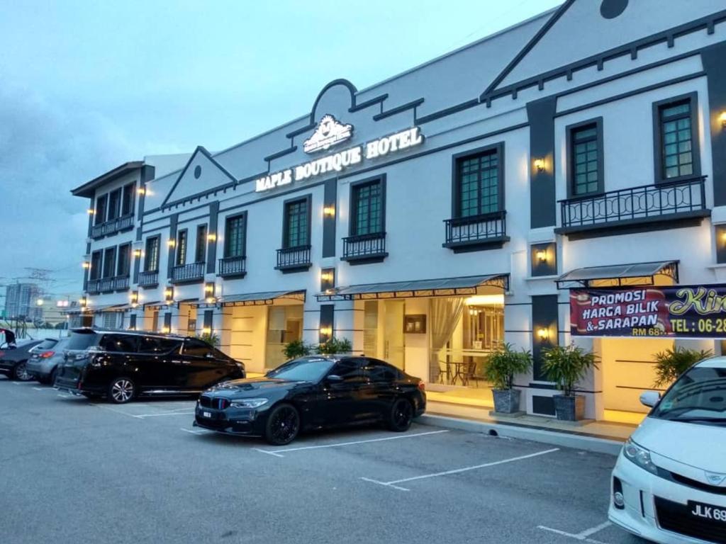 ein großes Gebäude mit Autos auf einem Parkplatz in der Unterkunft Maple Boutique Hotel in Malakka