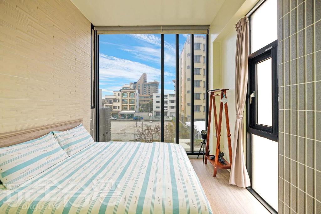 a bedroom with a bed and a large window at Penghu 123 V-Stone in Magong