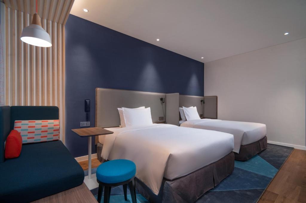um quarto de hotel com duas camas e uma cadeira em Holiday Inn Express Jinjiang Anhai, an IHG Hotel em Jinjiang