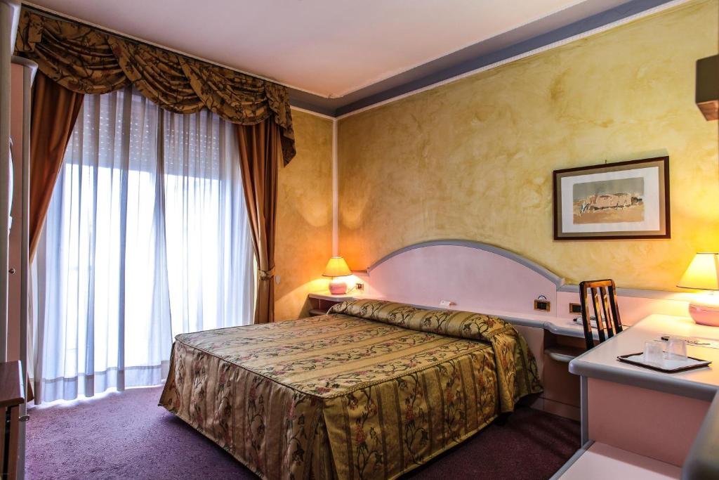 
a bedroom with a large bed and a large window at Hotel Grazia Deledda in Sassari
